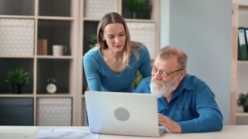 Woman Helping Senior Man With Computer at Home