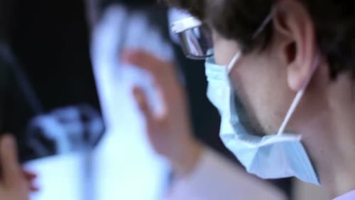 Doctor Examining Medical X-Ray with Surgical Mask and Glasses