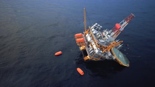 Collapsed offshore oil platform. Floating lifeboats in the sea. Oil Spill.
