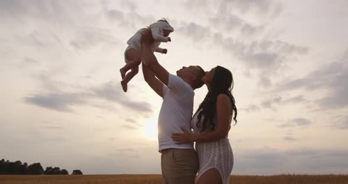 Loving Family Plays in Field at Sunset