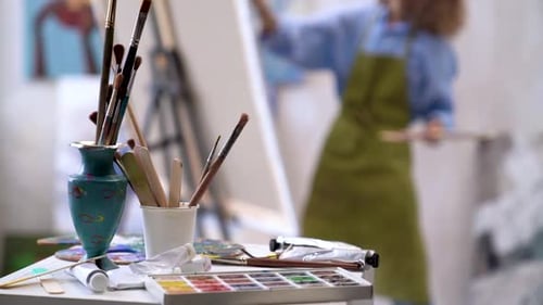 Art Supplies with Artist Painting on Canvas