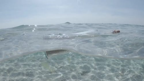 Glass bottle with message floats in transparent water of sea or ocean