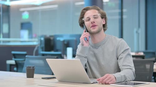 Young Adult Talking on Phone in Modern Office