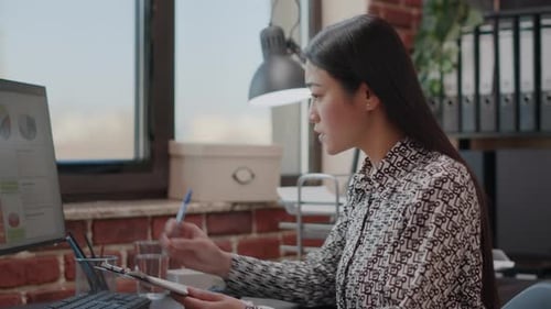 Business Woman Looking at Files on Clipboard to Work on Strategy