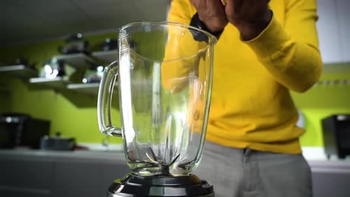 Person Adding Strawberries into Blender in Modern Kitchen