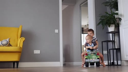 Brothers Playing Together on Toy Car Indoors