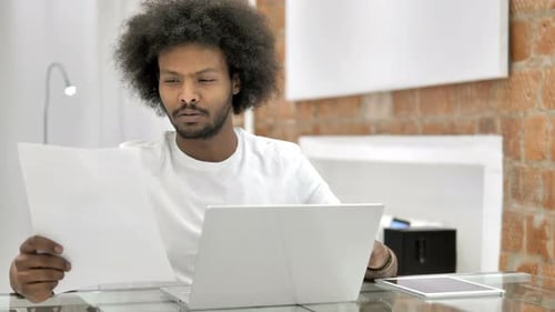 Young Adult Reviewing Papers at a Glass Desk
