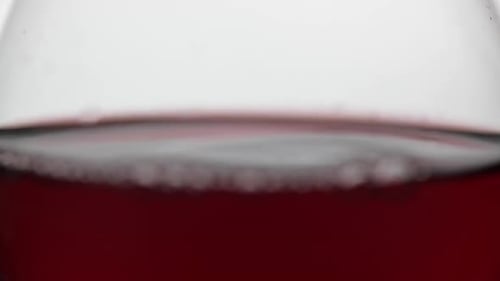 Close Up of a Drop Falling in Glass with Red Wine. Rose Wine on White Background