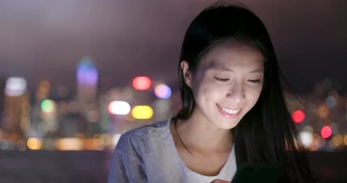 Woman use of mobile phone for online in Hong Kong at night