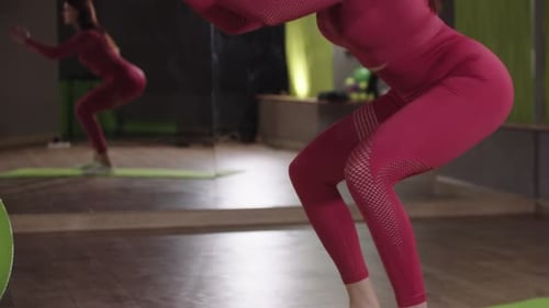 Fitness Training Young Woman in Pink Sportive Costume Doing Squats in the Mirror Fitness Hall