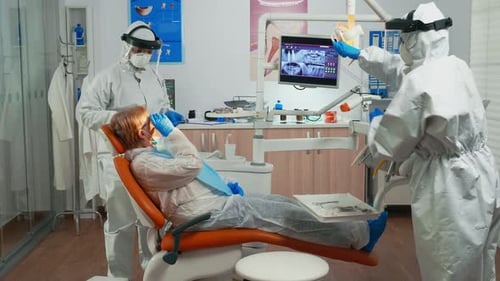 Dentist Examining Patient in Full Protective Gear