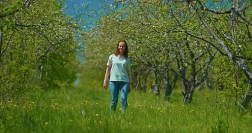 Young Woman is Walking in Blooming Garden in Spring Viewing Trees Prores