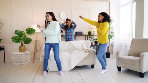Happy multiracial girls having dancing party at home