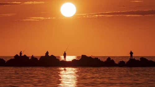 Sunset Fishing Silhouettes on Rocky Coastline