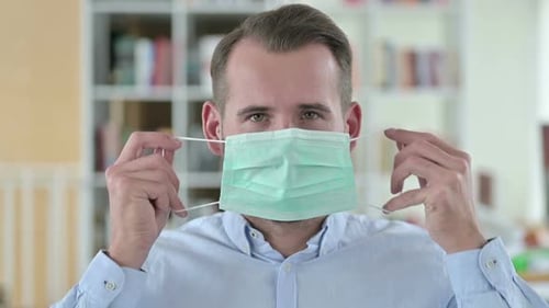 Man Puts on Protective Face Mask Indoors