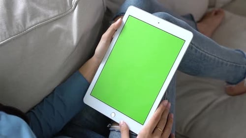 Mulher asiática de mãos dadas e assistindo usando um tablet com tela verde.