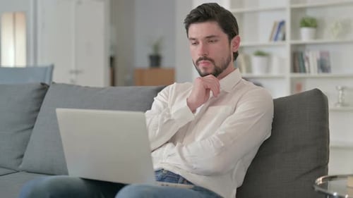 Thoughtful Man Working on Laptop at Home