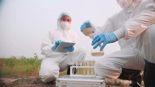 Two Biological engineer in full PPE took a sample of water in toxic area to check contaminants.