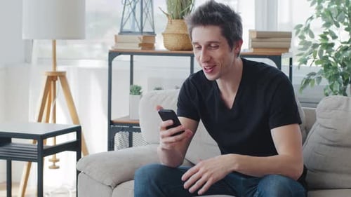 Young Man Video Calling on Smartphone at Home