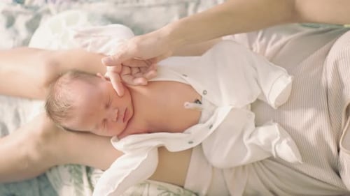 newborn baby top view lies on her lap mother caresses the child's hand