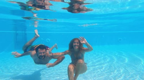 Happy caucasian people couple have fun and enjoy the swimming activity at the pool