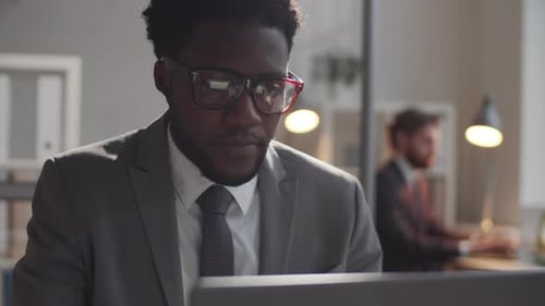 Cheerful Afro-American Businessman Using Laptop in Office