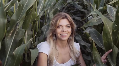 Woman Smiling and Touching Corn Stalks