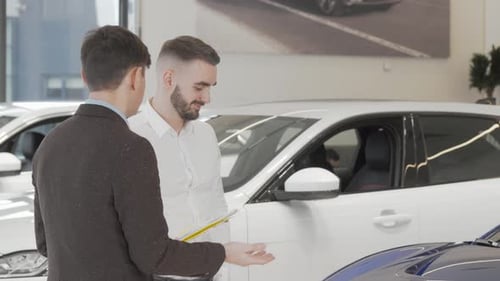 Handsome Businessman Talking to Salesman at Car Dealership