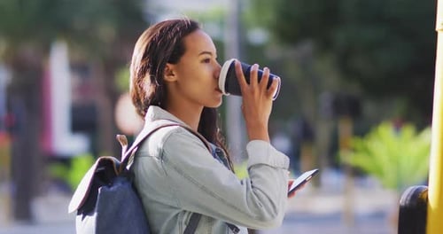 Young Woman Drinks Coffee Waiting on Urban Street
