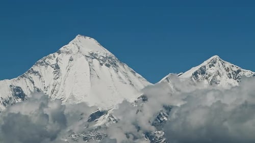 Timelapse Clouds Swirl Over a Mountain Valley a Snowy Peak in the Distance
