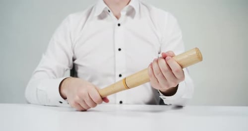 Man Shakes Wooden Baseball Bat at a Desk