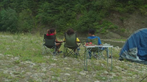 Rear View of Happy Diverse Multiracial Tourists Relaxing at Camping at Mountain Riverbank