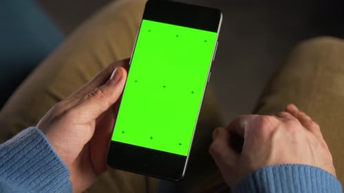 Man Using Smartphone with Green Mockup Screen in Vertical Mode