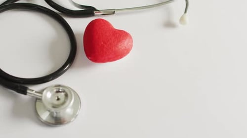 Video of close up of stethoscope with heart on pink background
