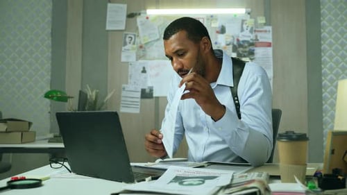 Detective Reviews Case Files at His Office Desk