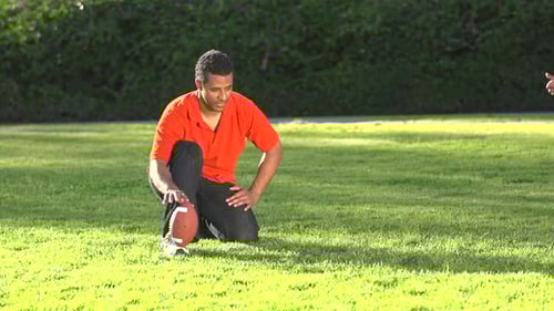 Father and Son Playing Football on Grassy Lawn