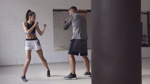In a Spacious Loft, a Male Trainer and His Female Mentee Conduct a Boxing Training Session