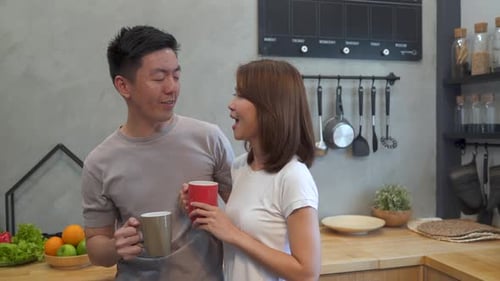 Young Couple Talking and Drinking Coffee in Kitchen