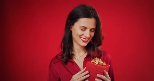 Smiling Woman Holding a Red Gift Box