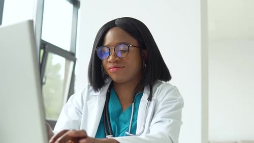 Female Doctor Typing on Laptop in Office Setting