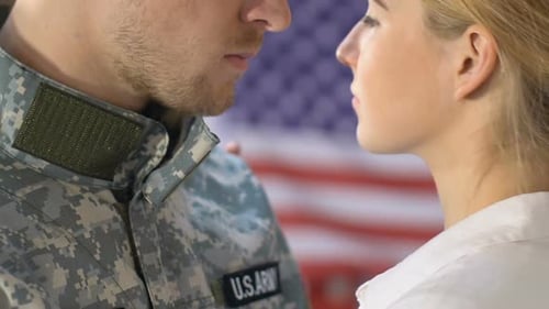 Serviceman and Woman Embracing in Front of Flag