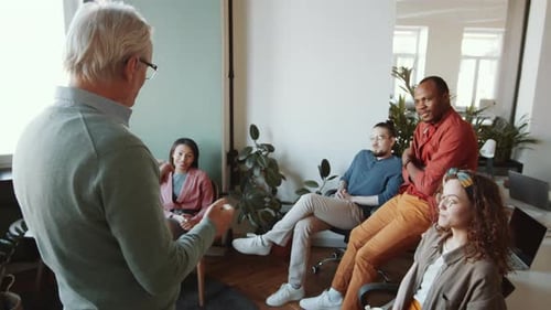 Senior Team Leader Talking to Young Multiethnic Workers in Office