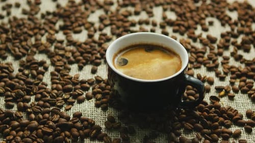 Steaming Coffee Cup Surrounded by Coffee Beans