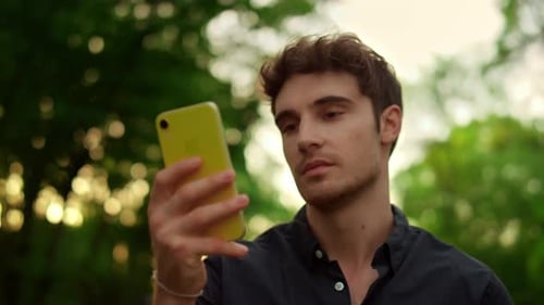 Portrait of Serious Man Reading Message on Mobile Phone During Walk in Park