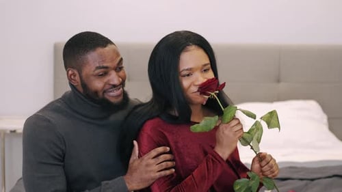 Romantic Couple with Rose in Cozy Bedroom Setting