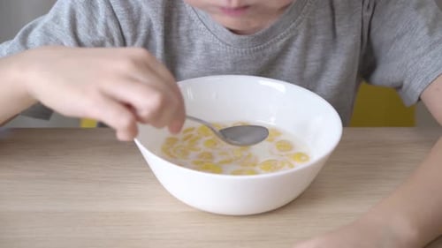 Child Eating Cereal at the Table Indoors