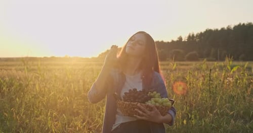 Young Girl Holding Basket of Grapes and Eating Grapes