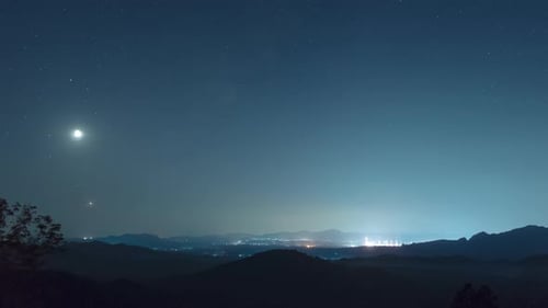 Mountainous Landscape at Night with Stars and City