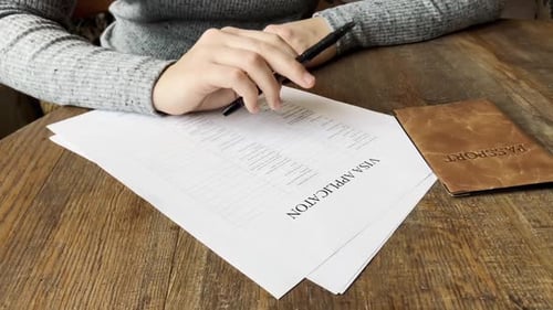 Filling Out Visa Application with Passport at Table
