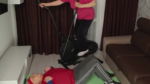 Senior Couple Exercising at Home with Dumbbells, Elliptical